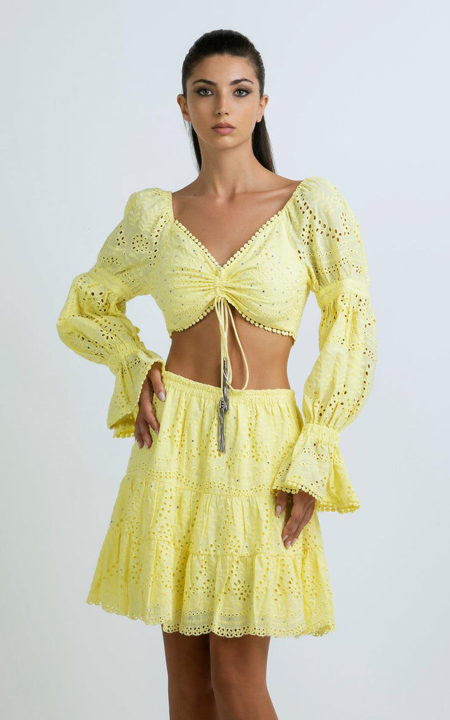 Woman wearing a yellow eyelet crop top and matching tiered skirt set with long sleeves