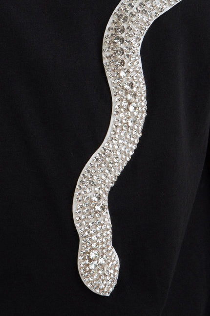 Close-up of black fabric with a sparkling rhinestone snake detail, women's fashion accent