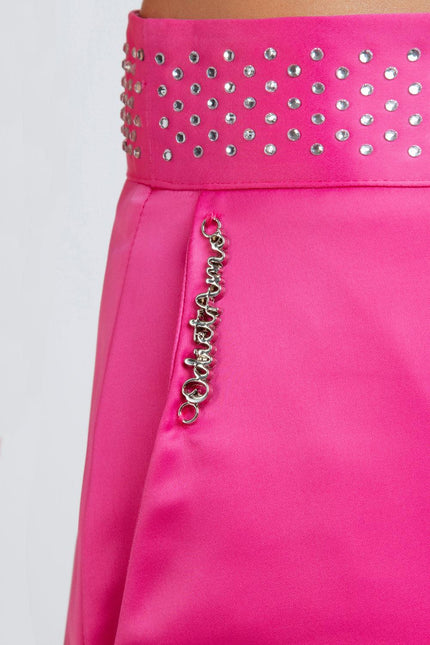 Close-up of pink high-waisted skirt with rhinestone detailing and silver metal logo charm