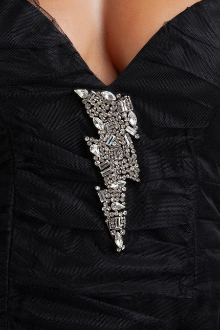 Black ruched dress with deep neckline and jeweled lightning bolt brooch detail