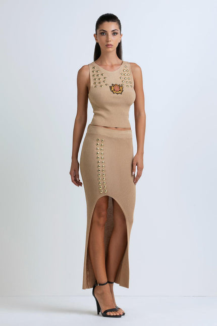 Woman wearing beige ribbed crop top and high-slit skirt with gold stud details