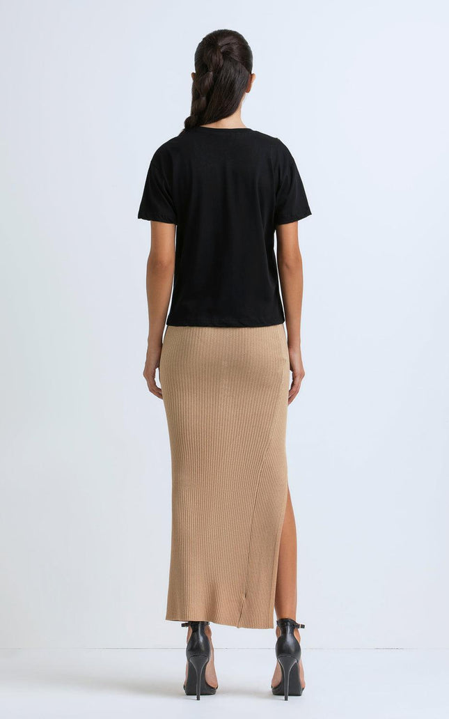 Woman in black t-shirt and beige ribbed midi skirt with slit, rear view