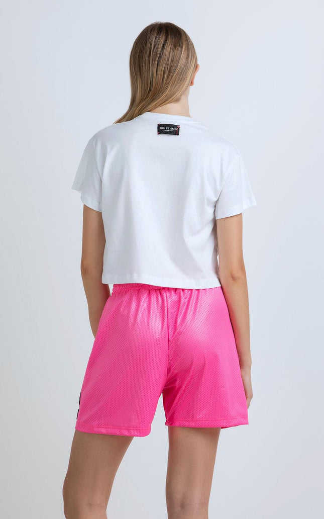 Woman wearing white crop top and bright pink mesh shorts, shown from the back