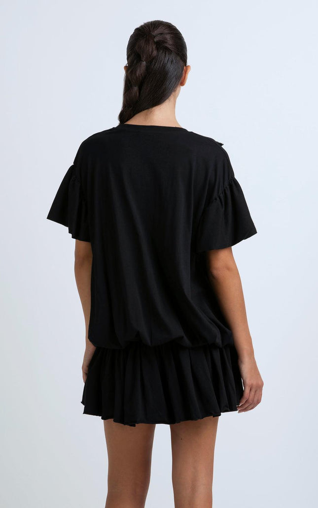 Woman in black short dress with ruffle sleeves and pleated skirt, back view