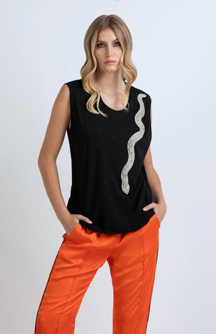 Woman in black sleeveless top with sequin snake detail and orange satin pants