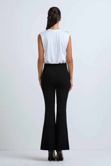 Woman wearing sleeveless white top and high-waisted black flared pants, back view