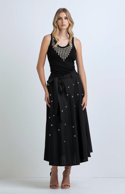 Woman in black sleeveless top with silver embellishments and matching black maxi skirt
