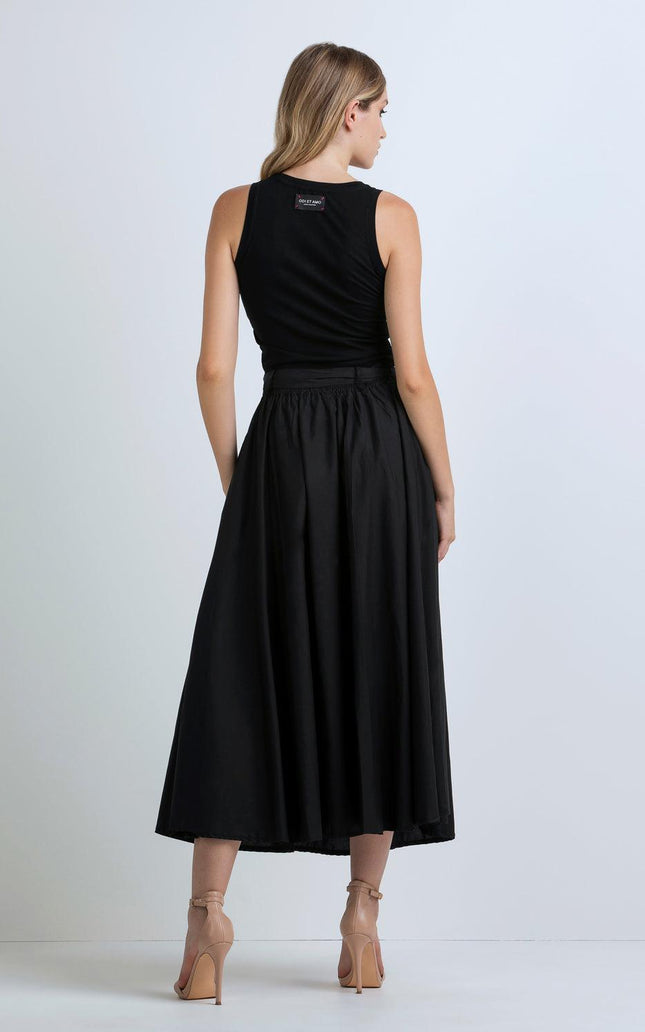 Woman in sleeveless black midi dress and nude heels, back view, against white background