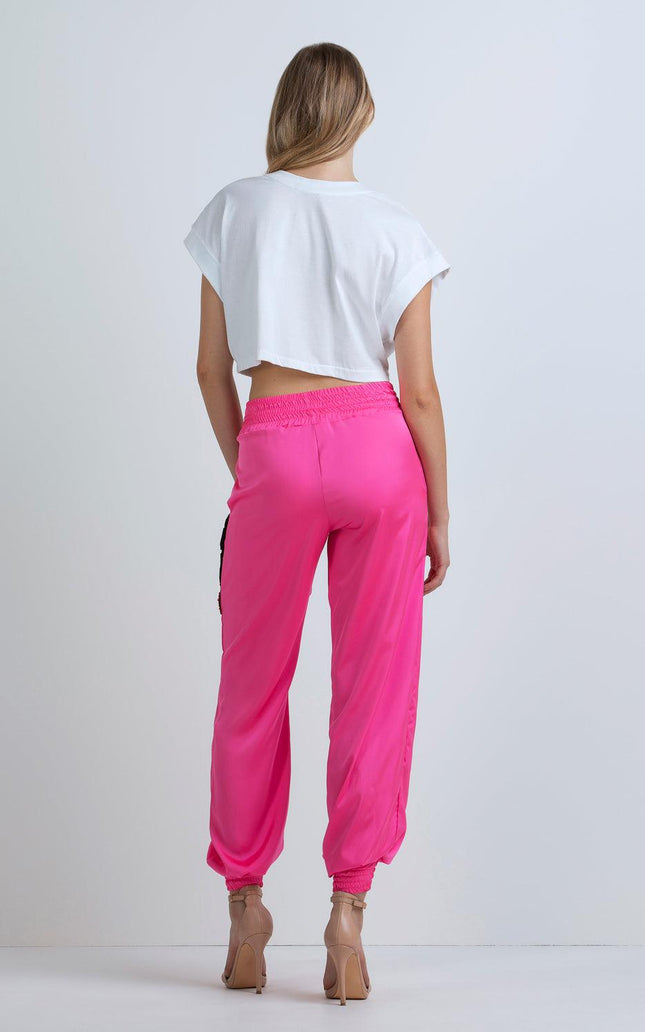 Woman wearing white crop top and high-waisted hot pink jogger pants, rear view