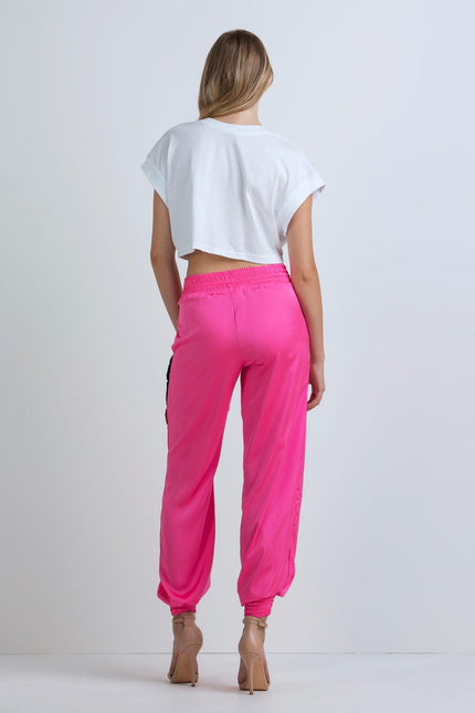 Woman wearing white crop top and high-waisted hot pink jogger pants, rear view