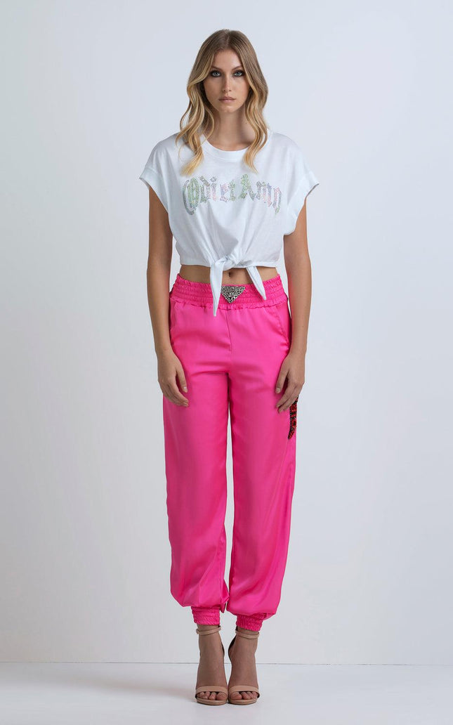 Woman wearing a white graphic tie-front crop top and bright pink jogger pants