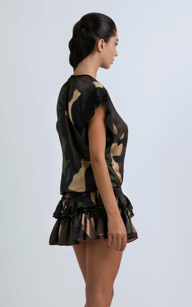 Woman in camouflage print ruffle mini dress, side view, against plain background