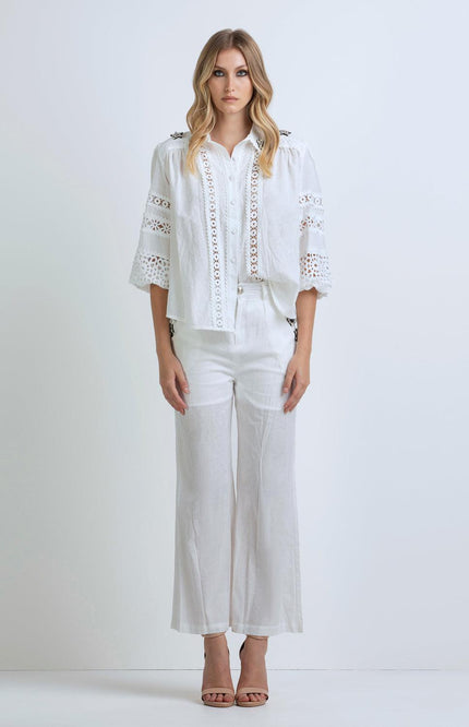 Woman wearing a white lace blouse with wide sleeves and white wide-leg pants