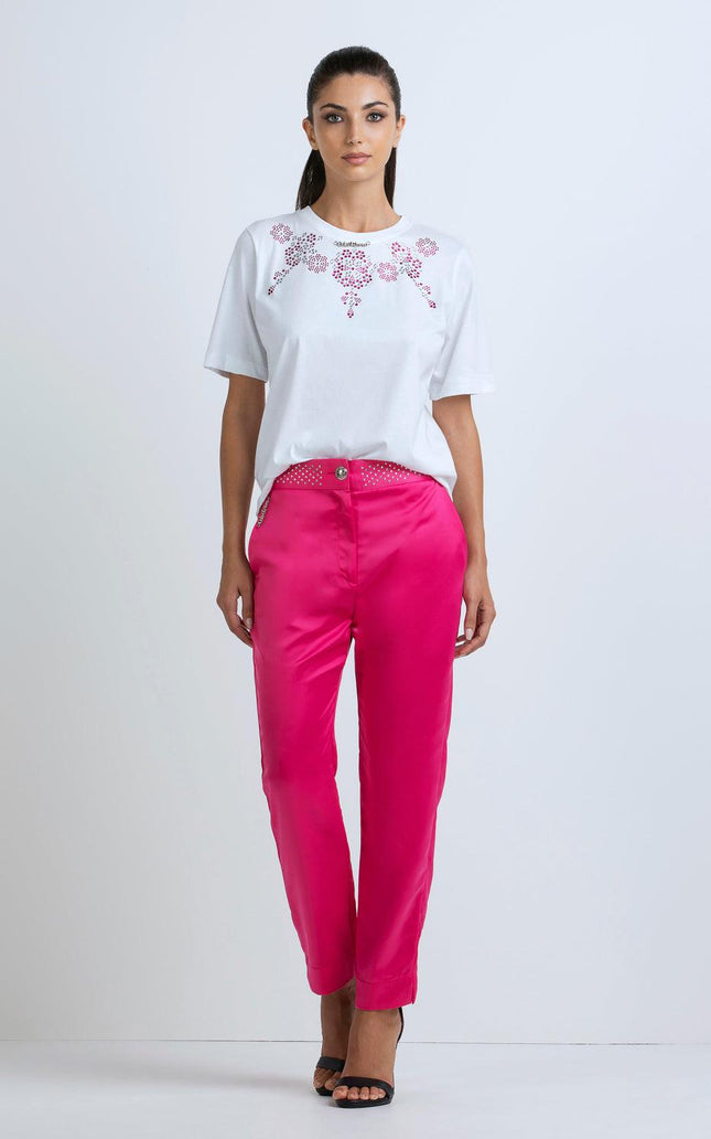 Woman wearing a white embellished t-shirt and bright pink satin pants, fashion outfit