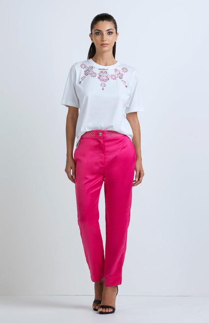 Woman wearing a white embellished t-shirt and bright pink satin pants, fashion outfit
