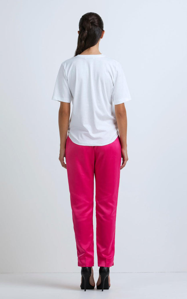 Woman wearing white t-shirt, bright pink pants, black high heels, shown from the back