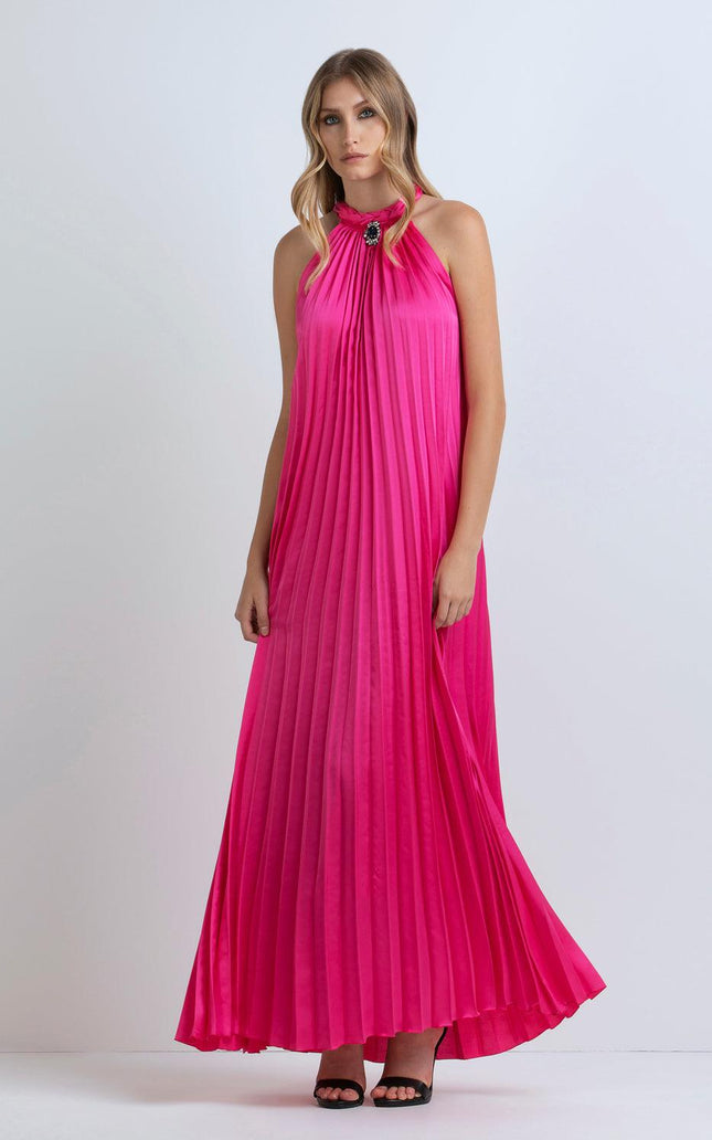 Woman wearing a pleated fuchsia maxi dress with halter neckline and jeweled detail