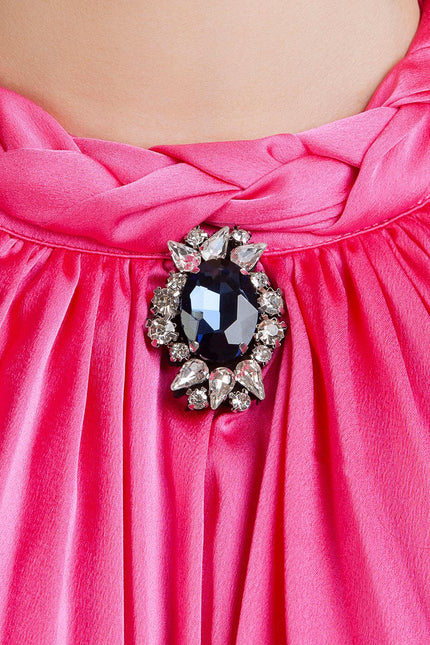 Pink pleated dress with crystal and black gemstone brooch detail at the neckline