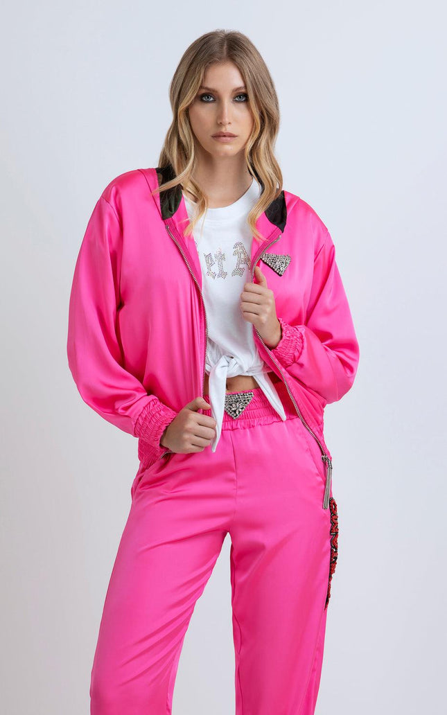 Woman wearing a vibrant pink satin tracksuit with rhinestone details and a white knotted T-shirt
