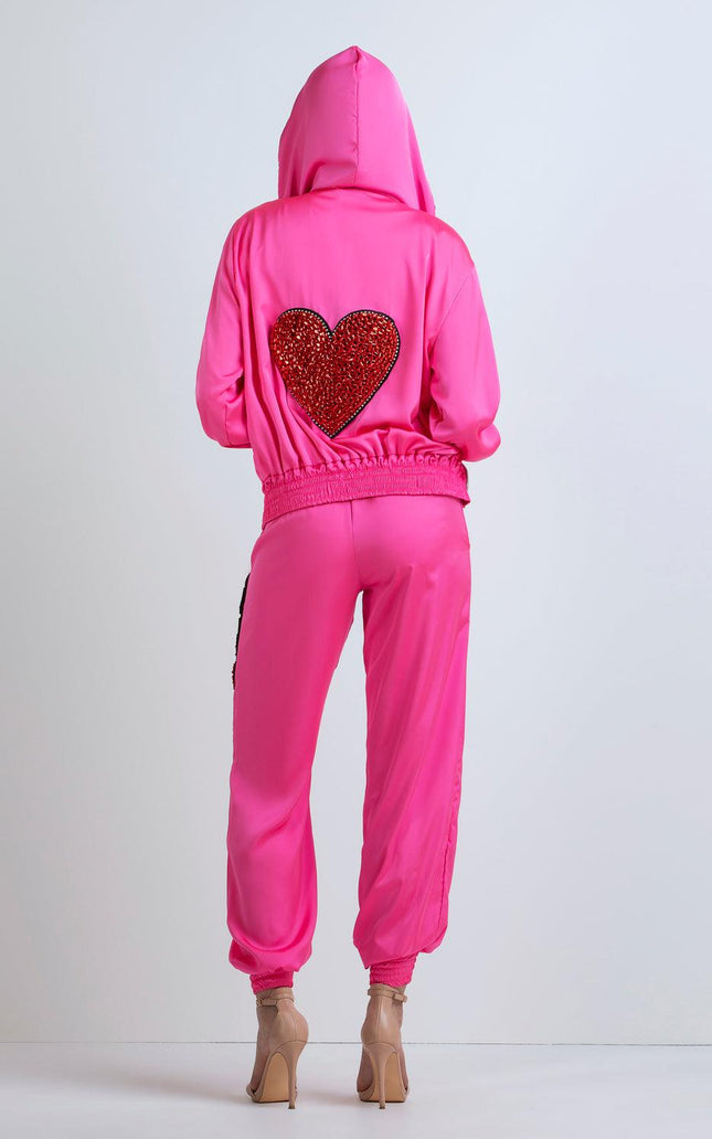 Back view of woman in a pink tracksuit with red sequin heart on hoodie, high heels