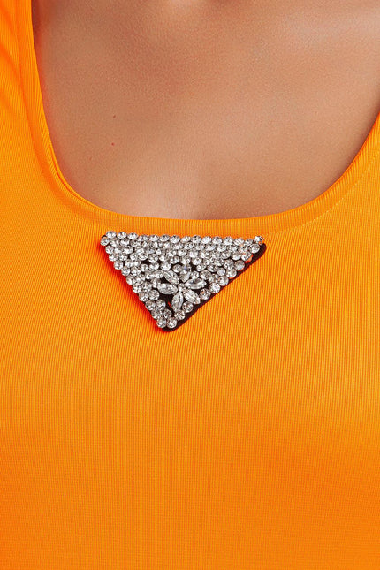 Close-up of orange dress with rhinestone triangle brooch on neckline, women's fashion