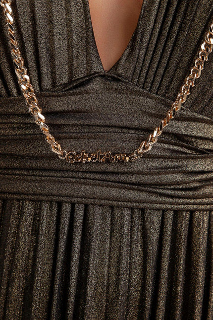 Gold chain necklace with script pendant over a shimmery black pleated dress close-up