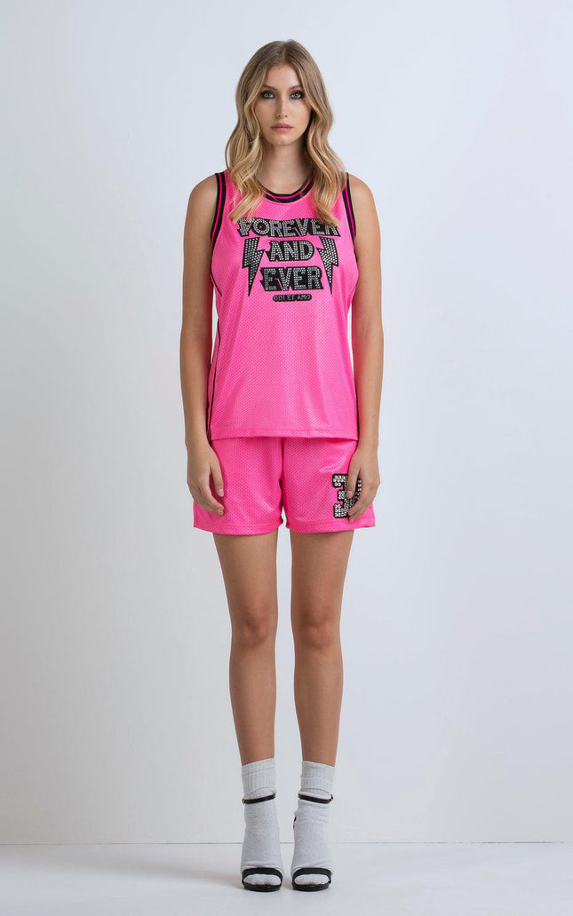 Woman wearing bright pink mesh tank top and shorts set with sporty chic style, text print, and socks with heels.