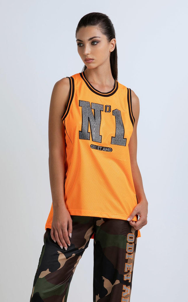 Woman wearing orange mesh sleeveless top with 'N°1' text and camo pants, fashion look