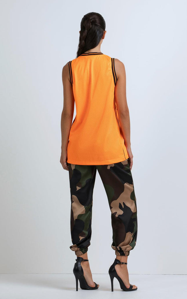 Woman in orange sleeveless top, camouflage joggers, and black high heels, back view