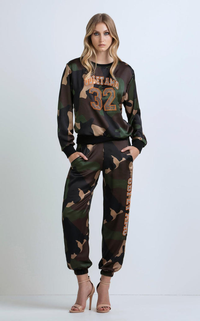 Woman wearing camo print tracksuit with crystal '32' detail and high heels, fashion look