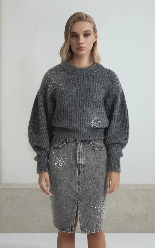 Woman wearing a grey knit sweater and denim skirt embellished with rhinestone details