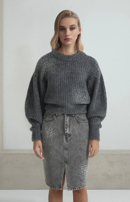 Woman wearing a grey knit sweater and denim skirt embellished with rhinestone details