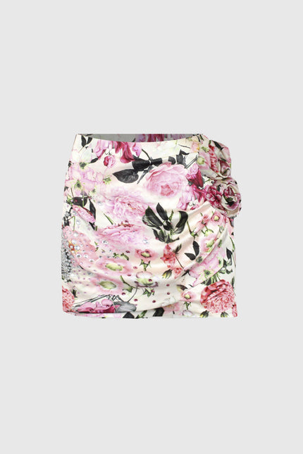 Mini skirt with pink floral print, ruched details and side flower accent on white background