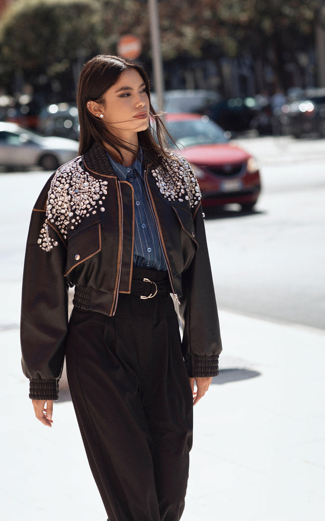 Woman wearing a black embellished cropped jacket and high-waisted pants, street style