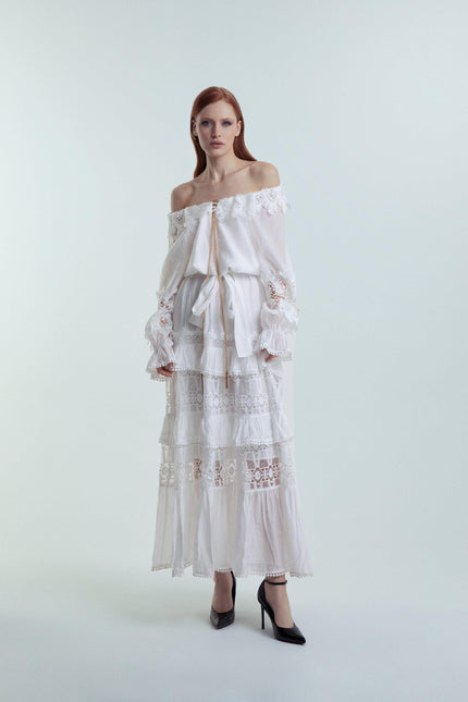 Woman wearing off-shoulder white lace maxi dress with ruffle details, fashion studio shot