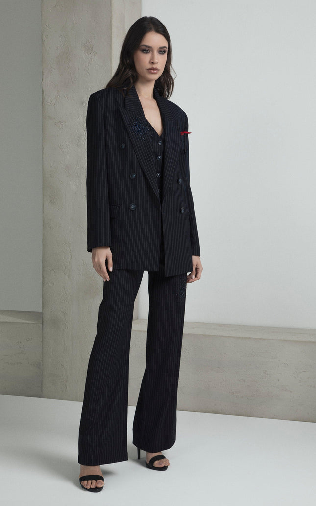 Woman wearing a black pinstripe suit set with wide-leg pants and open blazer in minimalist setting