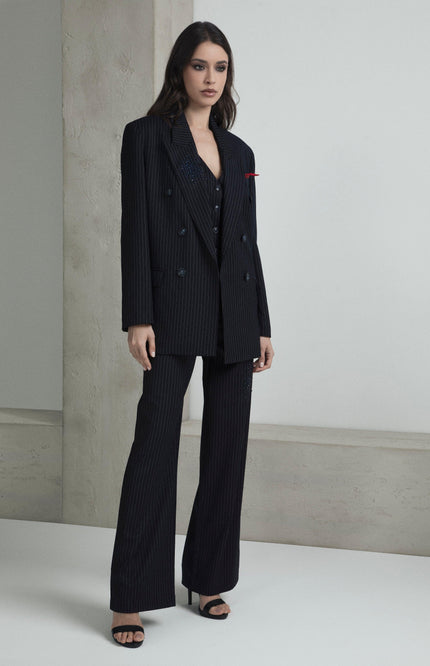 Woman wearing a black pinstripe suit set with wide-leg pants and open blazer in minimalist setting