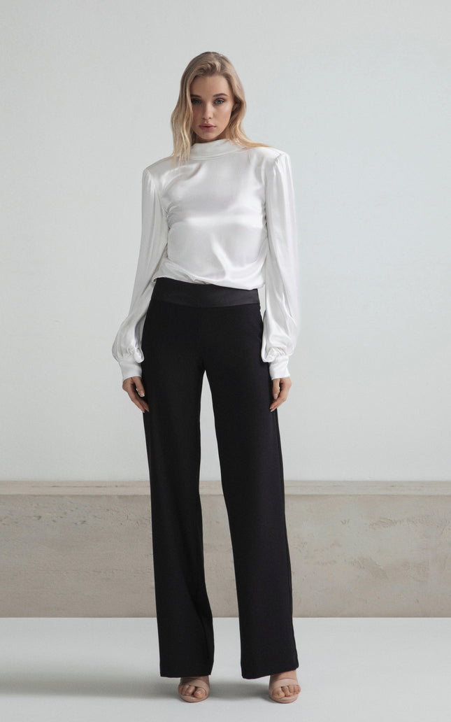 Woman in a white satin blouse and black wide-leg pants, minimal modern fashion