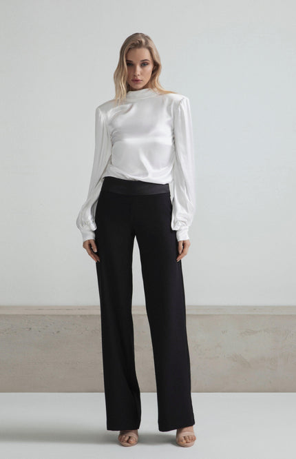 Woman in a white satin blouse and black wide-leg pants, minimal modern fashion