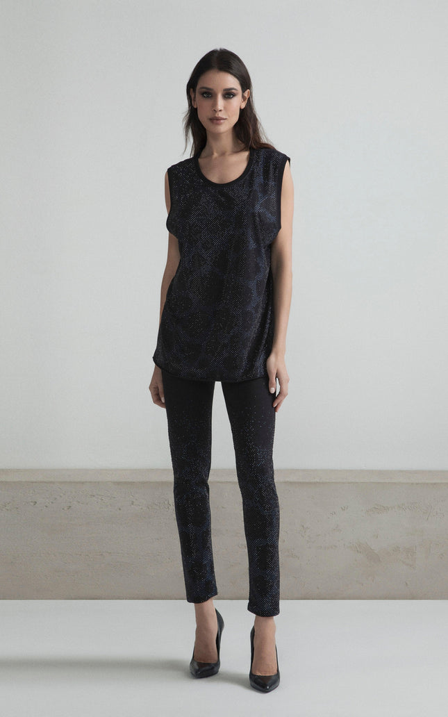 Woman wearing sleeveless black glitter top and slim pants, high heels, in minimalist room