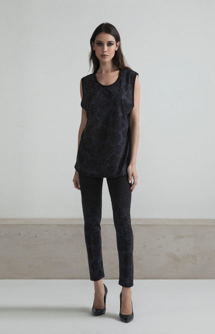 Woman wearing sleeveless black glitter top and slim pants, high heels, in minimalist room