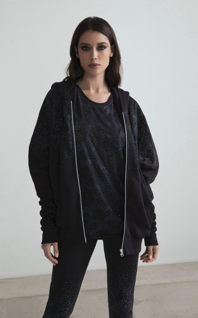 Woman wearing black sparkling hoodie, matching t-shirt and leggings, modern minimalist style