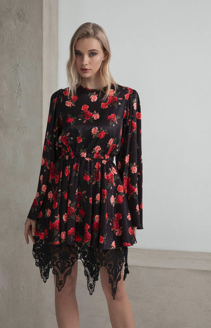 Woman wearing a black floral dress with red rose pattern and black lace hem