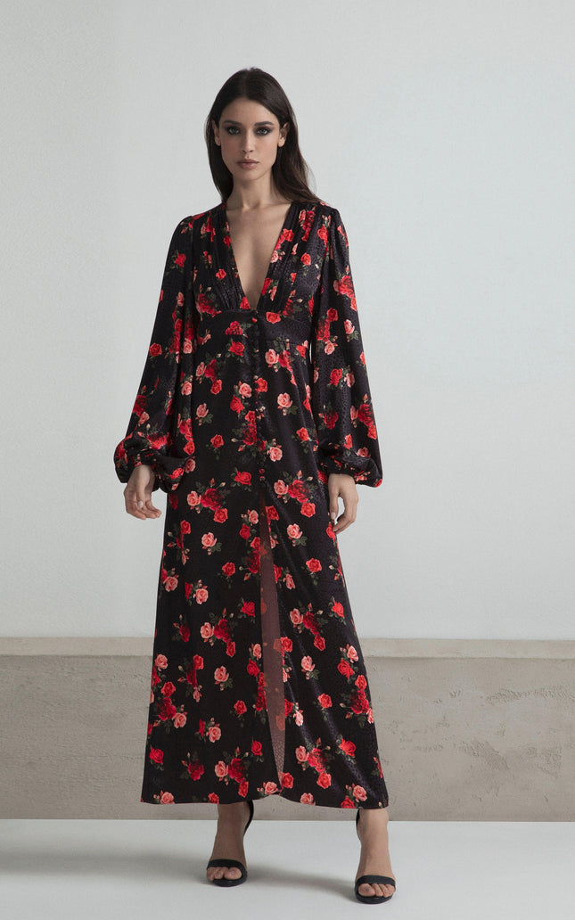 Woman wearing a long black floral dress with deep V-neck and long sleeves