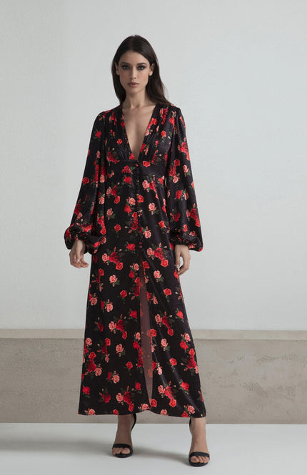 Woman wearing a long black floral dress with deep V-neck and long sleeves