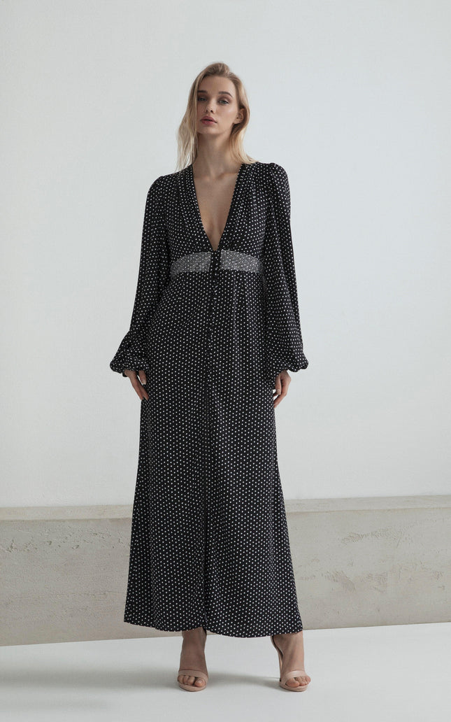 Woman in long black polka dot dress with deep V-neck and beaded waistband