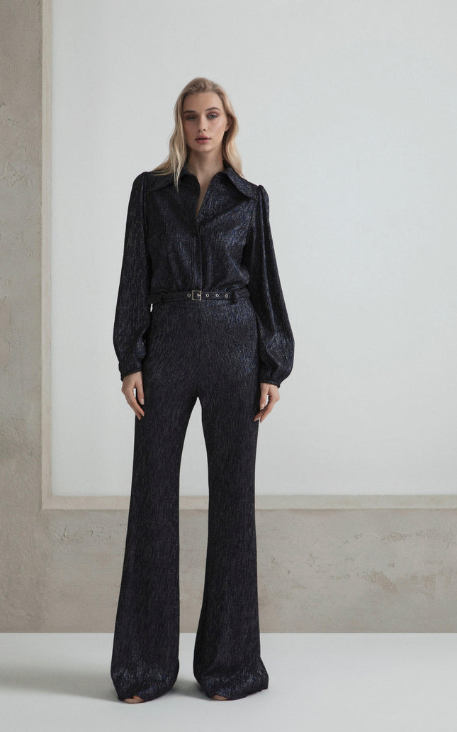Woman wearing a shimmery black belted jumpsuit with long sleeves and wide-leg pants
