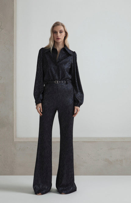 Woman wearing a shimmery black belted jumpsuit with long sleeves and wide-leg pants
