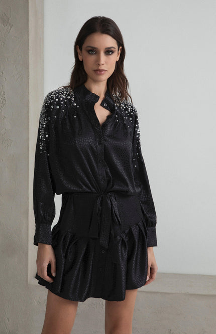 Woman wearing black satin mini dress with sequin details and button front, fashion look