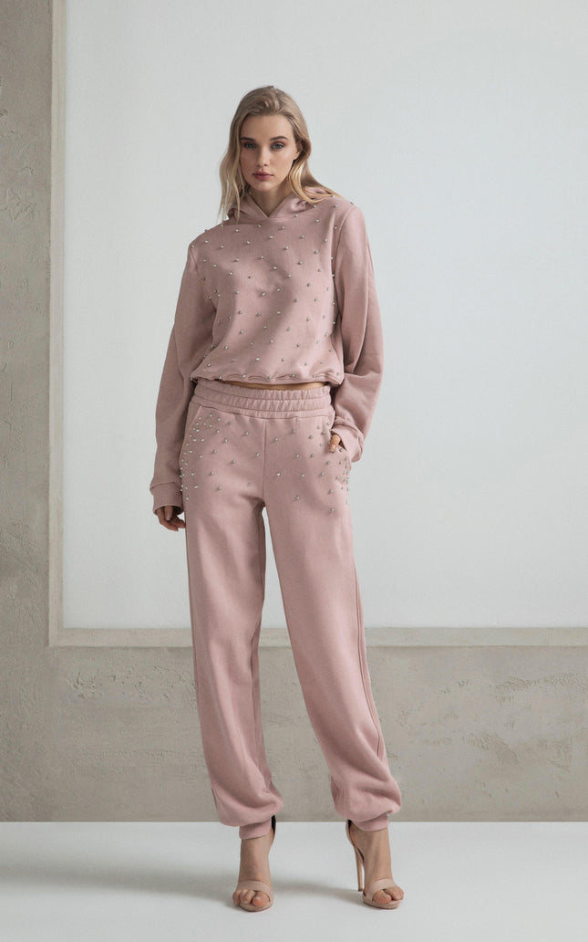 Woman wearing pink embellished sweatshirt and sweatpants set, neutral background